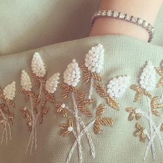 a close up of a person's arm with beaded flowers on it