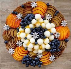 an overhead view of apples, oranges and blueberries on a platter with snowflakes