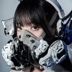 a woman with headgear and mask on posing for the camera in front of a gray background