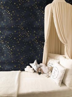 a white bed sitting next to a wall covered in stars