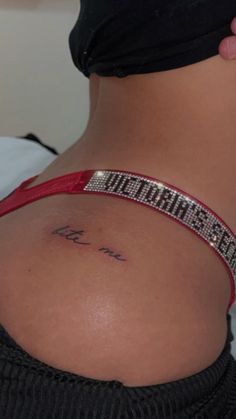 the back of a woman's stomach with a tattoo on her left side and words written in cursive writing