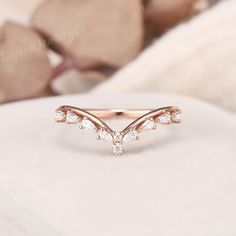 a rose gold ring with three small white stones in the middle, on top of a bed