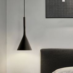 a bed with a black headboard and lamp hanging from the ceiling in a bedroom