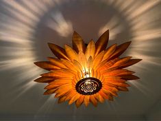 a light that is hanging from the ceiling with a sunflower design on it's side