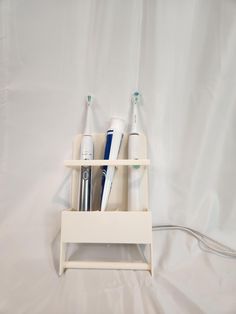 three toothbrushes and one electric toothbrush holder on a white sheeted background