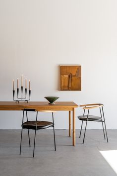 a wooden table sitting next to two chairs in front of a painting on the wall