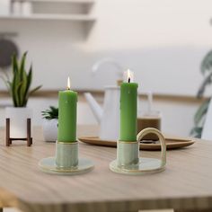 two green candles sitting on top of a wooden table