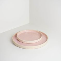 two pink and white plates sitting on top of each other in front of a white wall