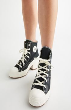 a person wearing black and white shoes with laces on them, standing in front of a white background