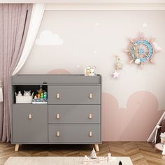 a baby's room with a dresser and wall decal in pastel colors