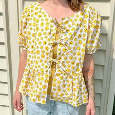 Upcycled adorable yellow and white smiley blouse with ties in the front. Made this with vintage cotton fabric and the lining is also cotton. The top includes 3 ties in the front, Juliet / puffy sleeves that include elastic for a comfortable fit. The bottom is a ruffled hem. Ganni inspired (bc who has $200 to spend on a shirt)  Measurements : laying flat it’s a 20-21” across the chest and from the neckline to the bottom it’s 23” it’s more of a L. Fabric has minor imperfections.    Home has a cat & dog; item is washed before going home w/ you! I also include washing instructions! Whenever I can I reuse packaging ♻️   #puffsleeve #peplumtop #handmade #vintage #upcycled #deadstock #y2k #kidcore #kidcorefashion #decora #reworked Funky Fabric, Reuse Packaging, Holiday Tops, Puffy Sleeves, Upcycled Vintage, Going Home, Vintage Cotton, Upcycle Clothes, Fashion Sewing