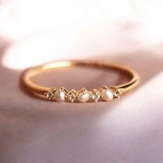 a gold ring with five pearls on it sitting on a white cloth covered tablecloth