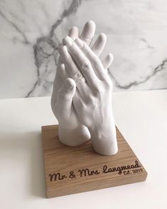 a white hand statue on top of a wooden base