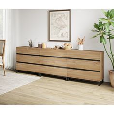 a living room with a large wooden dresser next to a plant