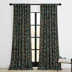 a room with a large window and floral curtains