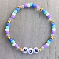 Mom Bracelet 💜🤍 Cute gift for mom! Add more bracelets to create the perfect stack, use kids names or grandkids names. Customize colors and charm ✨✨ Made with 4mm seed beads, bicone beads and gold filled beads ✨ CARING TIPS FOR YOUR JEWELRY ⭐️Treat and store with care. ⭐️ For longevity, avoid exposing your jewelry to water. ⭐️ Avoid having direct contact with lotions, perfumes, sanitizers as these chemicals may cause discoloration of your jewelry. Mom Bracelet Ideas, Casual Letter Beads Stretch Bracelet For Mother's Day, White Casual Beaded Bracelets For Mother's Day, White Casual Stretch Bracelet For Mother's Day, Casual White Beaded Bracelets For Mother's Day, Casual White Stretch Bracelet For Mother's Day, Mother's Day Gift Bracelets With Round Beads, Adjustable Beaded Bracelets As Gift For Mom, Casual Letter Beads Bracelets For Mother's Day