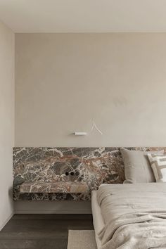 a bed sitting next to a wall with a stone headboard on top of it