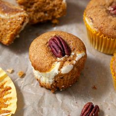 several cupcakes with frosting and pecans around them on a piece of wax paper