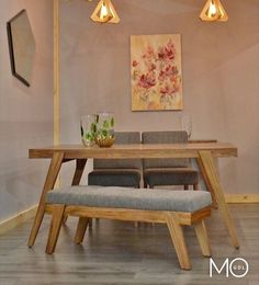 a dining room table with four lights hanging from it's ceiling and two chairs at the end