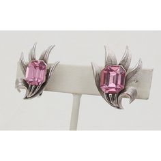 This is part of Chairish’s Costume Jewelry assortment.  1960s textured silvertone "fronds" with emerald cut faux-pink peridot rhinestone clip back earrings. Marked "Trifari." Measure: 1.25 inches L x 0.81 inches W. Condition: Very Good; small signs of wear.  Please reference the measurements noted in the description above for the best approximate dimensions. Please reach out to the seller under "Ask the Seller" for specific questions regarding the measurements. Vintage Trifari Jewelry, 1960s Jewelry Sets, Vintage Multicolor Clip-on Earrings For Party, Vintage Multicolor Rhinestone Jewelry, Vintage Trifari Earrings, 1960s Jewelry, Crown Trifari, Accessories Jewelry Earrings, Modern Branding