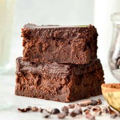 three brownies stacked on top of each other next to a banana and glass of milk