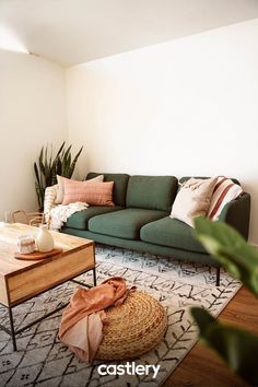 a living room with a green couch, coffee table and potted plant in the corner