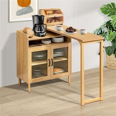 a small wooden table with some plates and cups on top of it, next to a potted plant