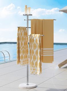 two yellow towels are hanging on a towel rack near the water's edge,