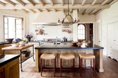 a kitchen with wooden floors and an island in the center, surrounded by stools