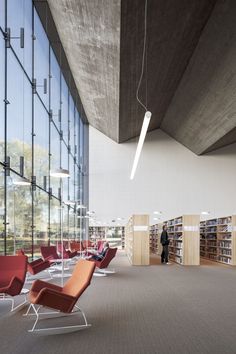 an empty library with many chairs and bookshelves on the walls, in front of a large window