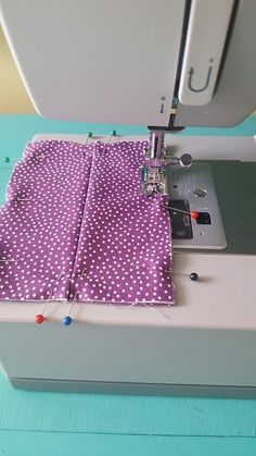 the sewing machine is working on the purple polka dot fabric that has been sewn