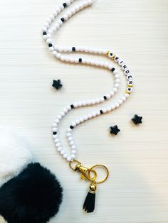 a white beaded necklace with black tassels and a keychain