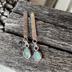 two pairs of earrings sitting on top of a piece of wood