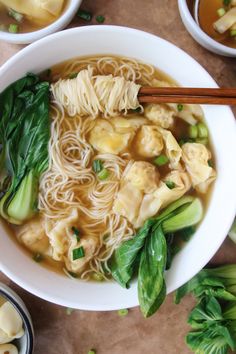 a white bowl filled with noodles and veggies next to some chopsticks