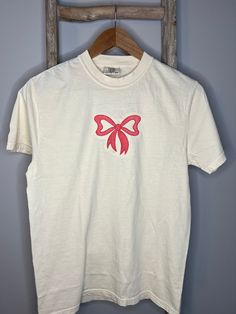 Pink Bow Embroidered Tee This is the cutest girly pink bow embroidered tee! It is perfect for every day or to dress it up!  Comfort Colors brand shirt; fits true to size. Available in sizes: S-2X Cute Tshirt Embroidery, Casual Short Sleeve T-shirt With Pink Bow, Spring Cotton T-shirt With Bow, Pink Embroidered Cotton T-shirt, White Short Sleeve Tops With Bow, Pink Embroidered T-shirt, Vintage Short Sleeve Tops For Gift, Pink T-shirt With Floral Embroidery And Short Sleeves, Spring Crew Neck T-shirt With Bow