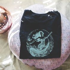 We love this fun, colorful unisex Teal Vintage Mermaid design T-shirt! This tee is soft and super comfy and is made of 100% cotton. Heather tees are a soft cotton-poly blend. We use BELLA+CANVAS for our T-shirts! FABRICATION * Solid Colors: 100% Ringspun Cotton * Heather Colors: 52% cotton, 48% polyester * Runs true to size SIZING This style is a unisex t-shirt. If you are unsure about the size you should order, please refer to the size chart in the pictures. CARE INSTRUCTIONS * Machine wash: warm (max 40C or 105F) * Tumble dry: low heat * Do not iron directly on print * Do not dryclean PRODUCTION TIME / SHIPPING TIME *Please click the "Shipping and Policies" tab under each listing photo to view our current production time. Note: these are custom items that are printed when ordered.  Items Mermaid Shirts, Mermaid Tshirt, Mermaid Design, Mermaid Shirt, Vintage Mermaid, Mermaid Birthday, Vintage Shirt, Design T Shirt, Vintage Shirts