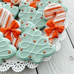 decorated cookies in the shape of christmas trees on a lace doily with bowknots