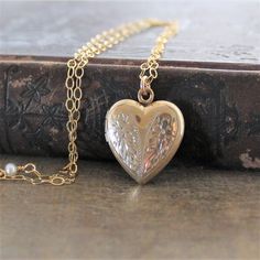 This vintage locket is engraved with a floral design on the front; the reverse is plain.  The heartshaped pendant opens revealing two compartments in which to place your favorite photos.  The locket hangs from a new 14k gold filled textured chain accented with tiny pearls the clasp.    ★Personalize the locket with our charms:https://www.etsy.com/shop/lexiandgem?section_id=6307004Locket 24x20mmNecklace length 18" (45cm)✦All of our vintage lockets ship with complimentary insurance✦✤Our entire sele Elegant Heart Shaped Filigree Locket Necklace, Anniversary Filigree Pendant Locket Necklace, Elegant Heart-shaped Engraved Locket Necklace, Wedding Jewelry Medallion With Heart Charm, Traditional Locket Jewelry For Keepsake, Valentine's Day Gold Necklace With Intricate Design, Heirloom Necklaces With Intricate Design For Anniversary, Victorian Jewelry With Heart Charm For Keepsake, Victorian Jewelry With Heart Charm As Keepsake