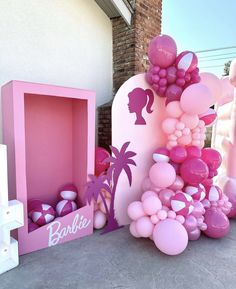 there is a pink box with balloons in it and a palm tree on the outside