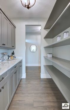 an empty kitchen with gray cabinets and white counter tops, along with wood flooring