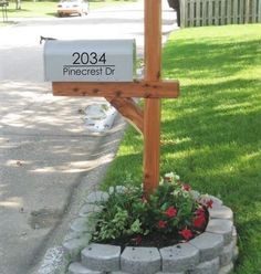 a wooden cross sitting on the side of a road next to a flower pot filled with flowers