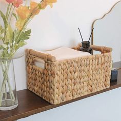 a wicker basket sitting on top of a shelf next to a vase with flowers