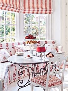 a dining room table with chairs and a bench in front of a window that has curtains on the windowsill