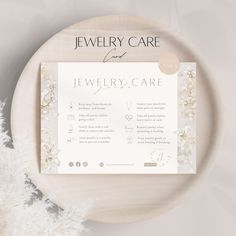 the jewelry care card is displayed on a plate with white flowers and feathers around it