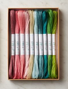 six skeins of multicolored yarn in a wooden box