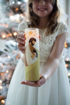 a woman in a white dress holding up a paper tube with an image on it