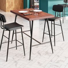 a kitchen table with two chairs and a bar stool next to it in front of a blue wall