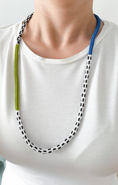 a woman wearing a white shirt with a blue and green beaded necklace on her neck