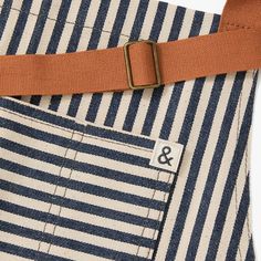 an orange belt is attached to a blue and white striped bag with brown leather straps