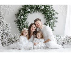 a family posing for a photo in front of christmas wreaths and pine tree branches